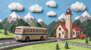 Autocar en pâte à modeler sur une route de montagne autrichienne, devant une église à clocher bulbeux